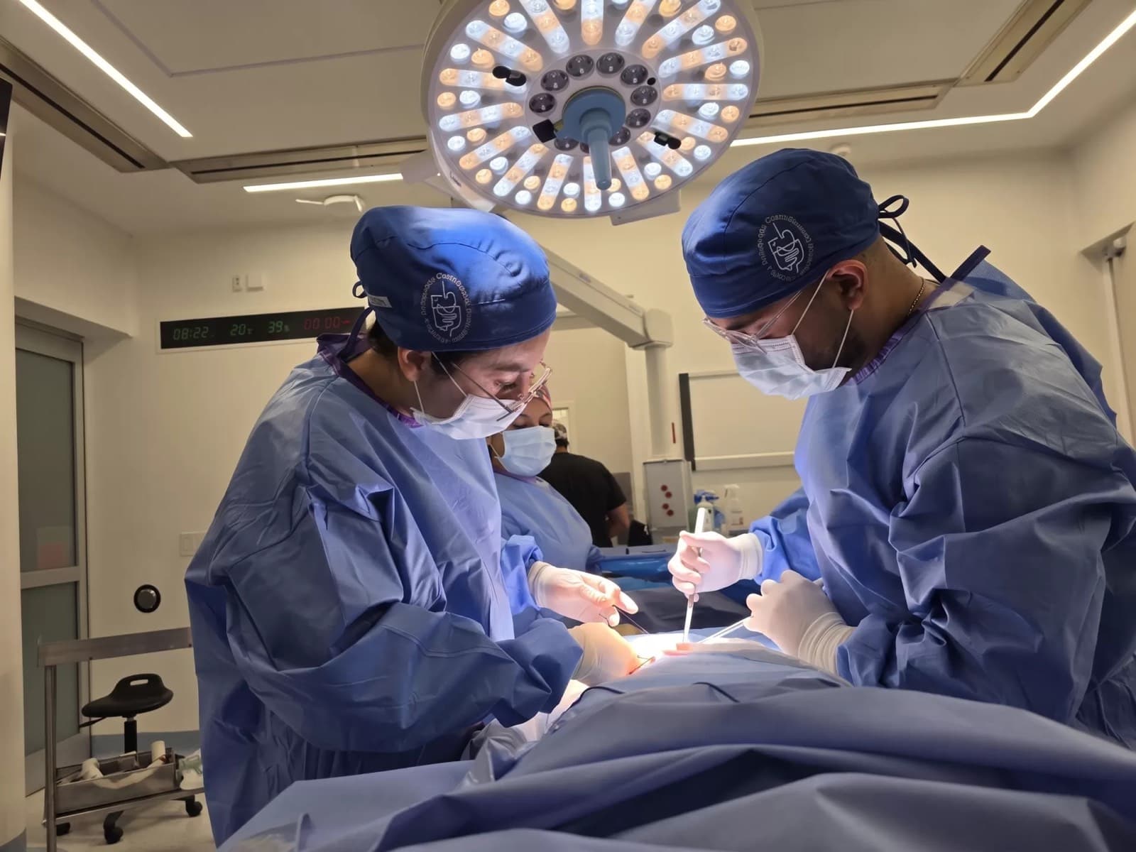 Dra. Diana Chavarría operando junto a otro cirujano bajo la lámpara de quirófano
